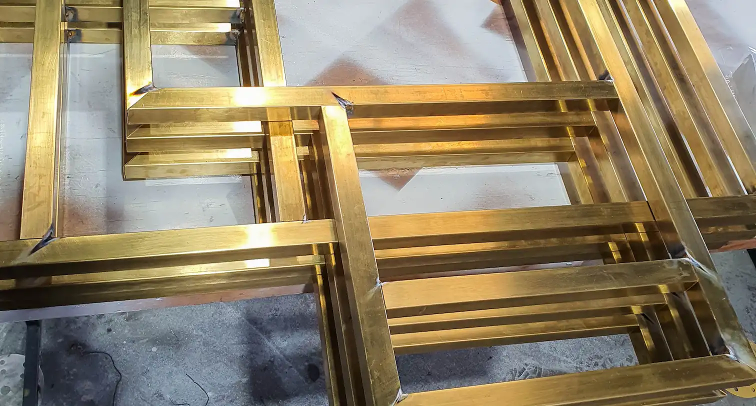 Stainless gold metal frames piled on the ground, pieces of a larger decorative interior project