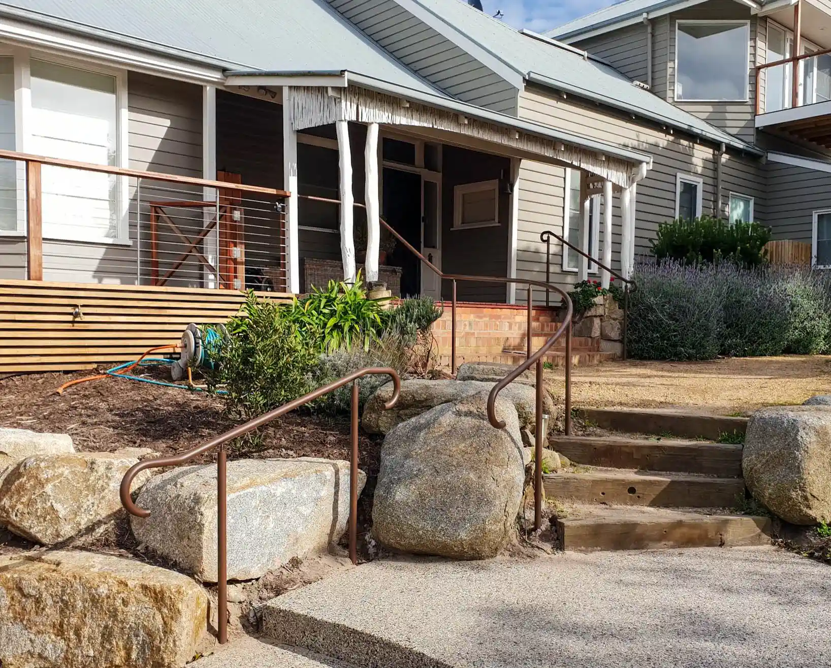 Brown metal hand railing adorning steps to a modern suburban home, front entrance