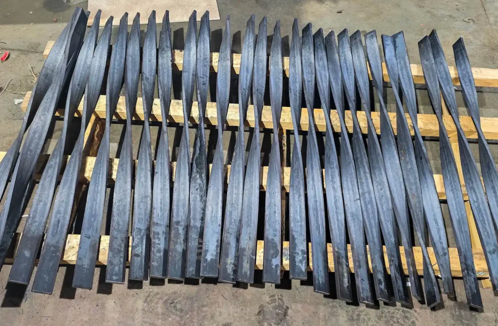 Long, twisted iron beams laying on a wooden pallet, ready to be added to a larger project